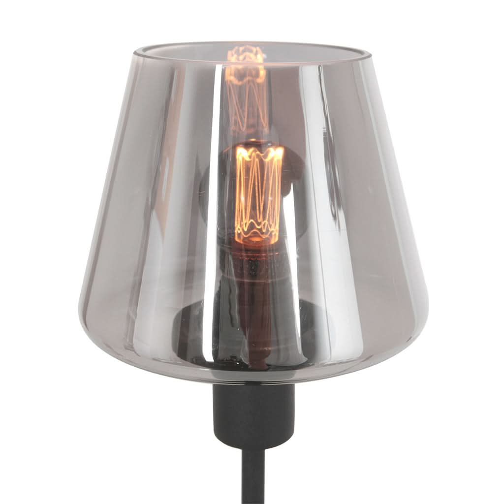 Détail rapproché du verre fumé, de la douille noire et de l'ampoule à filament allumée.