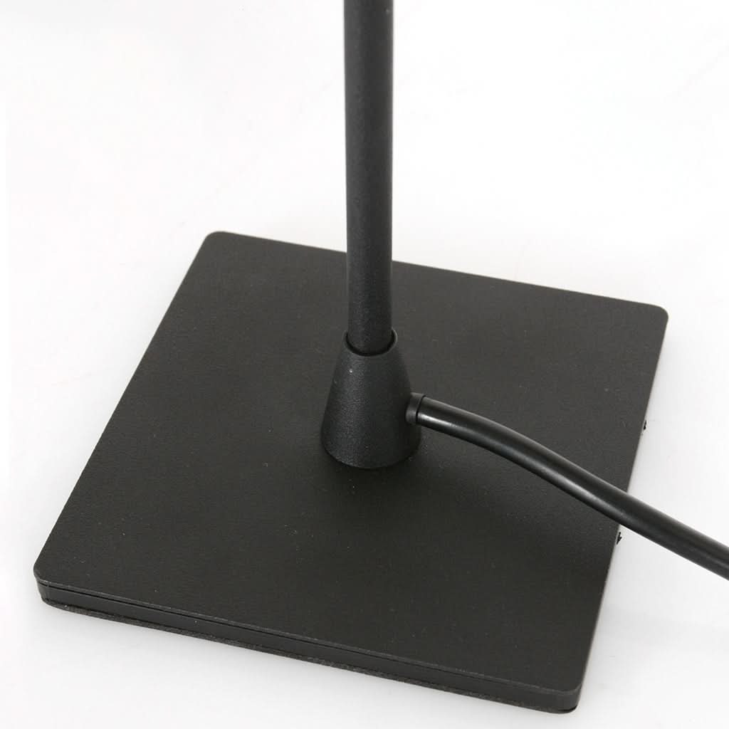Détail de la base carrée noire avec le câble d'alimentation sortant sur le côté.