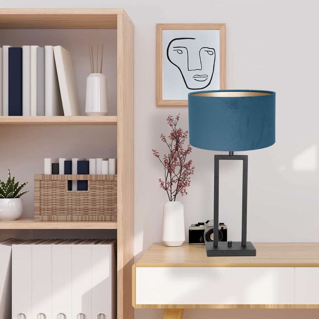 Mise en ambiance de la lampe posée sur un meuble en bois avec étagère et cadre.
