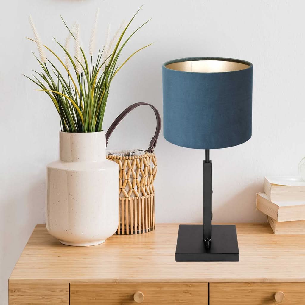 Lampe bleue posée sur une commode en bois, près d'un vase et d'un panier