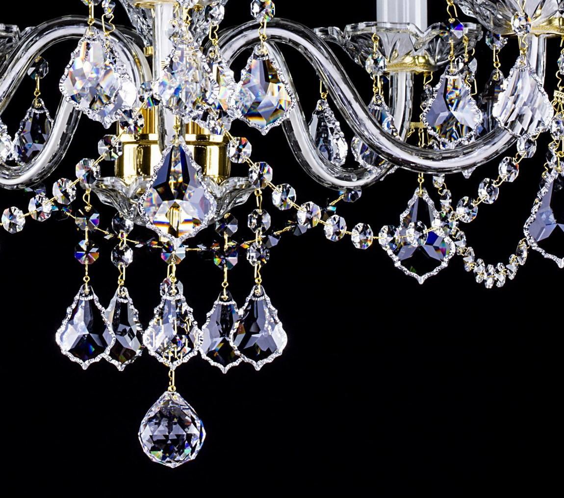 Gros plan sur les bras courbés et les pendentifs en cristal du lustre.