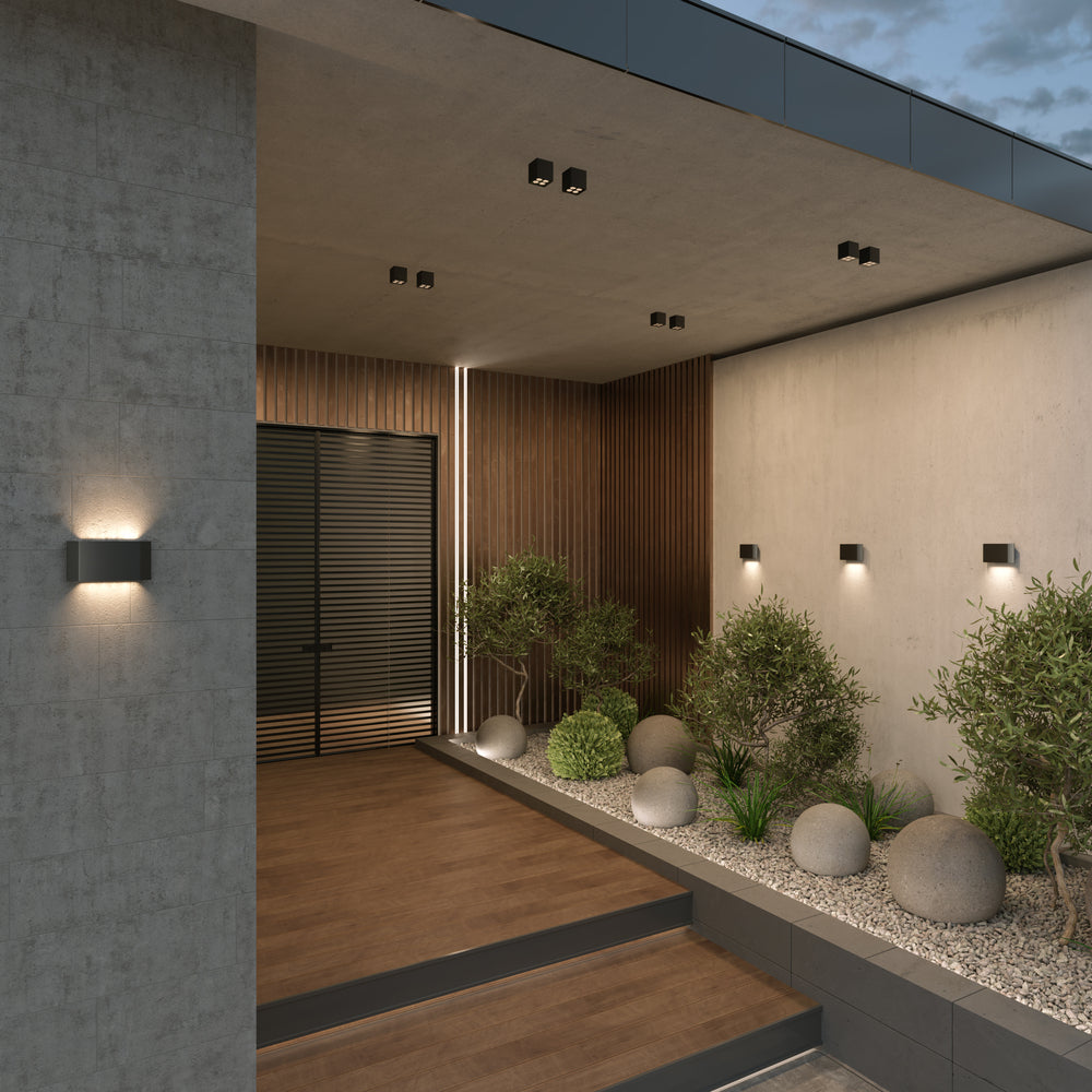 Mise en ambiance extérieure sur terrasse en béton et bois, mur éclairé.
