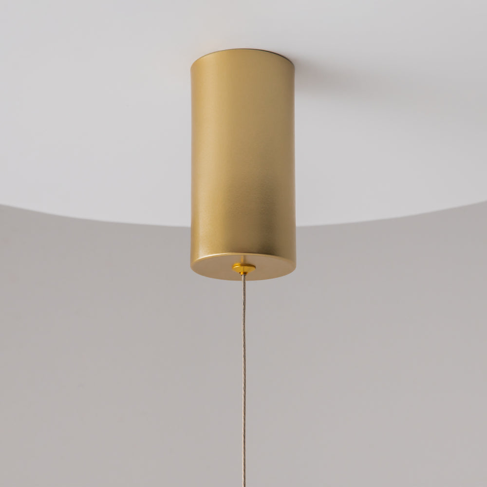 Détail du plafonnier doré cylindrique vu de dessous avec câble fin