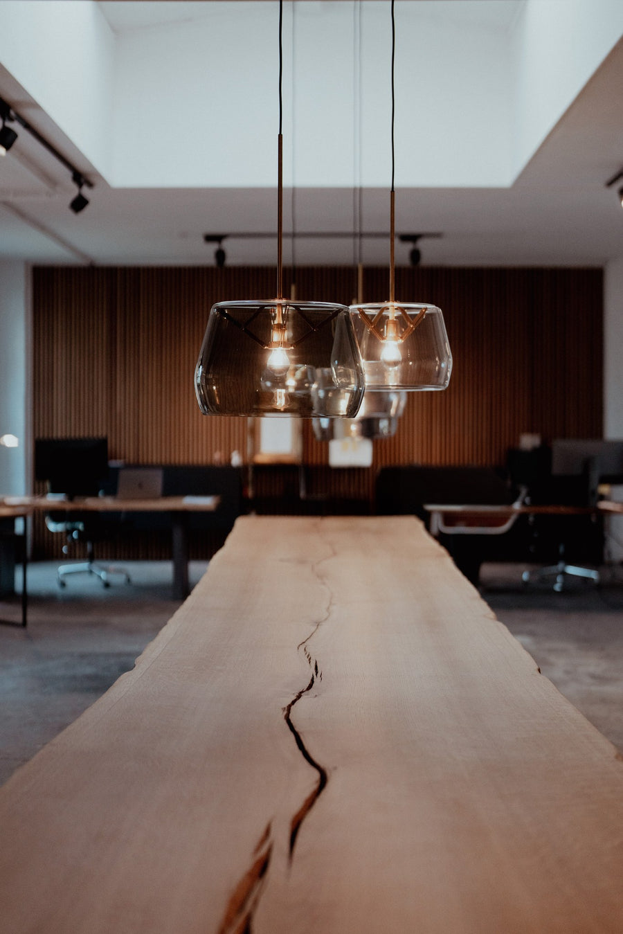 Suspension en verre soufflé transparent suspendue au-dessus d'une longue table en bois massif