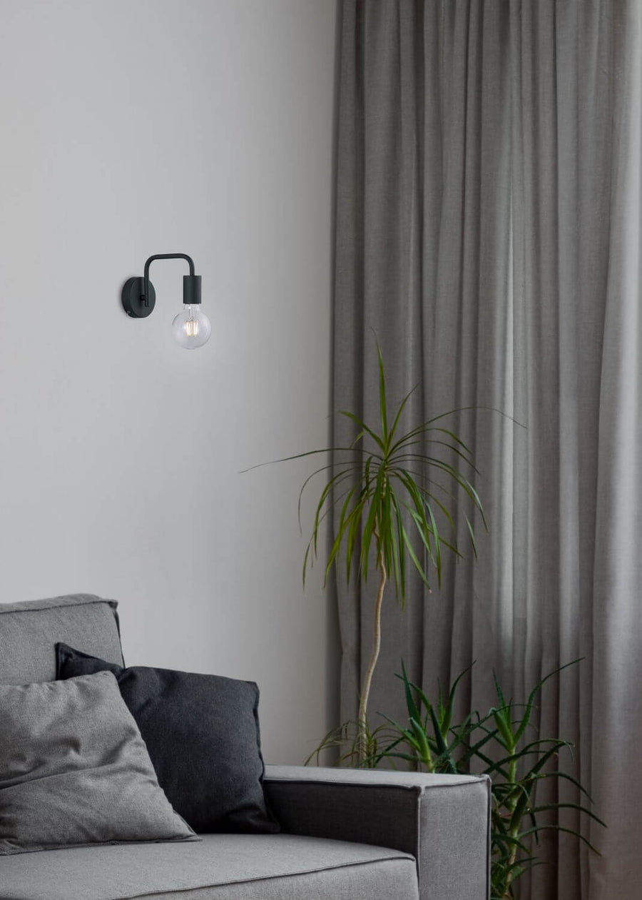 Vue rapprochée de l'applique noire avec ampoule globe transparente et rideaux gris
