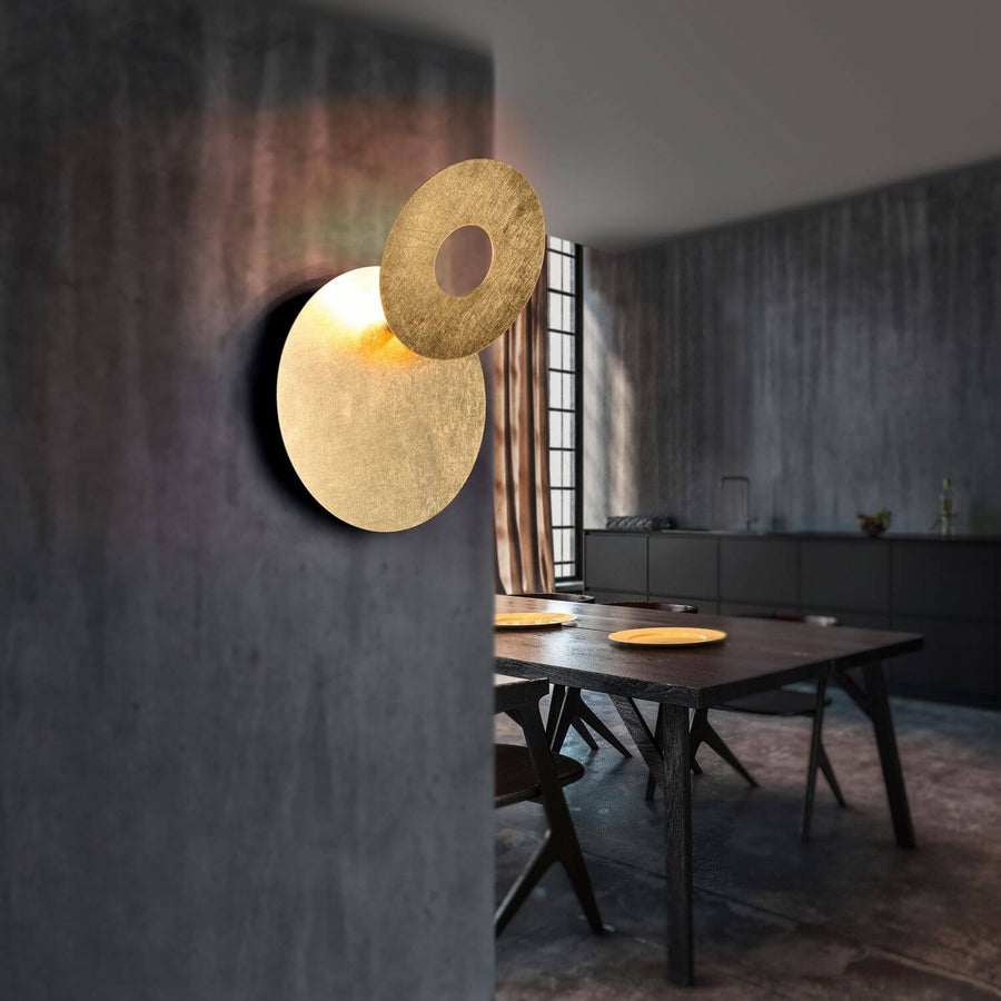 Applique dorée allumée fixée sur un mur gris, intérieur contemporain en arrière-plan
