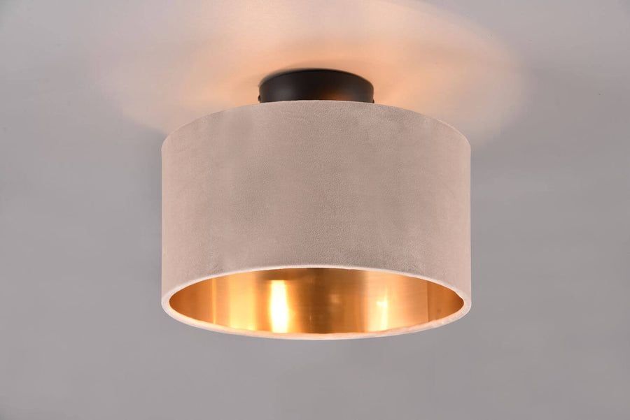 Gros plan sur l'abat-jour cylindrique en tissu suédé beige et son intérieur doré