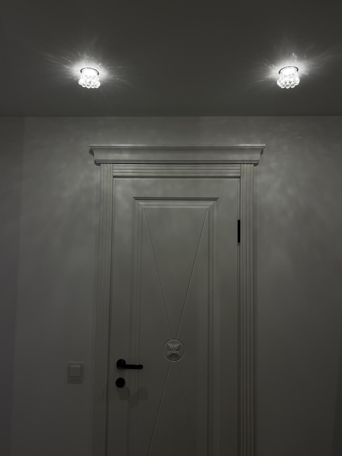 Deux spots allumés fixés au plafond de part et d'autre d'une porte grise.