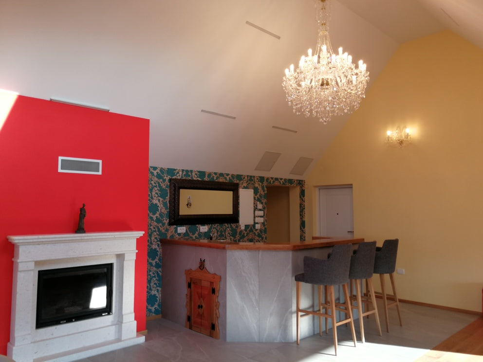 Lustre suspendu dans un salon avec mur rouge, cheminée et comptoir de bar