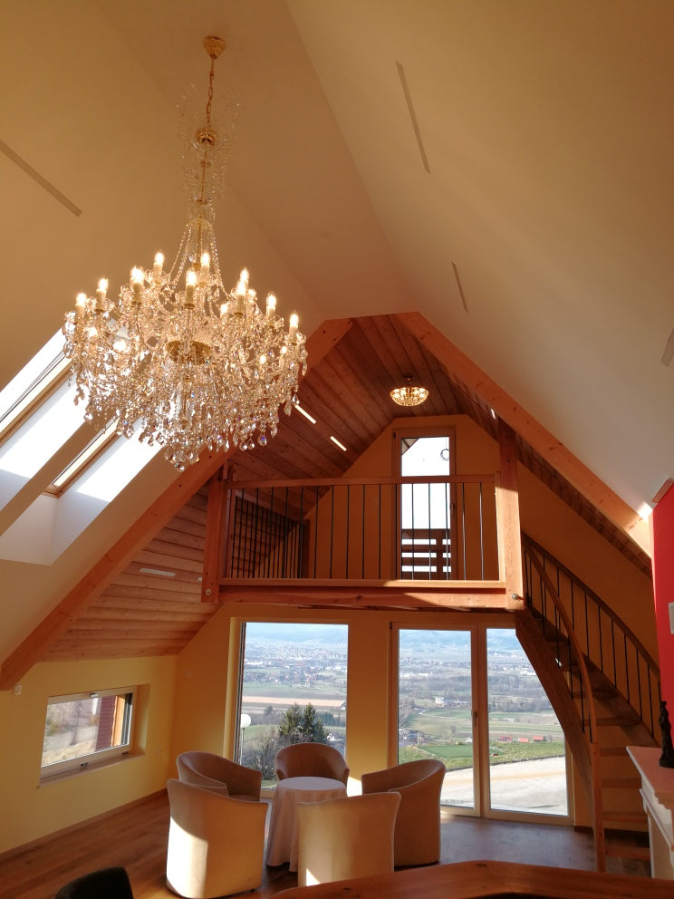 Lustre allumé sous une charpente en bois avec mezzanine et grandes baies vitrées