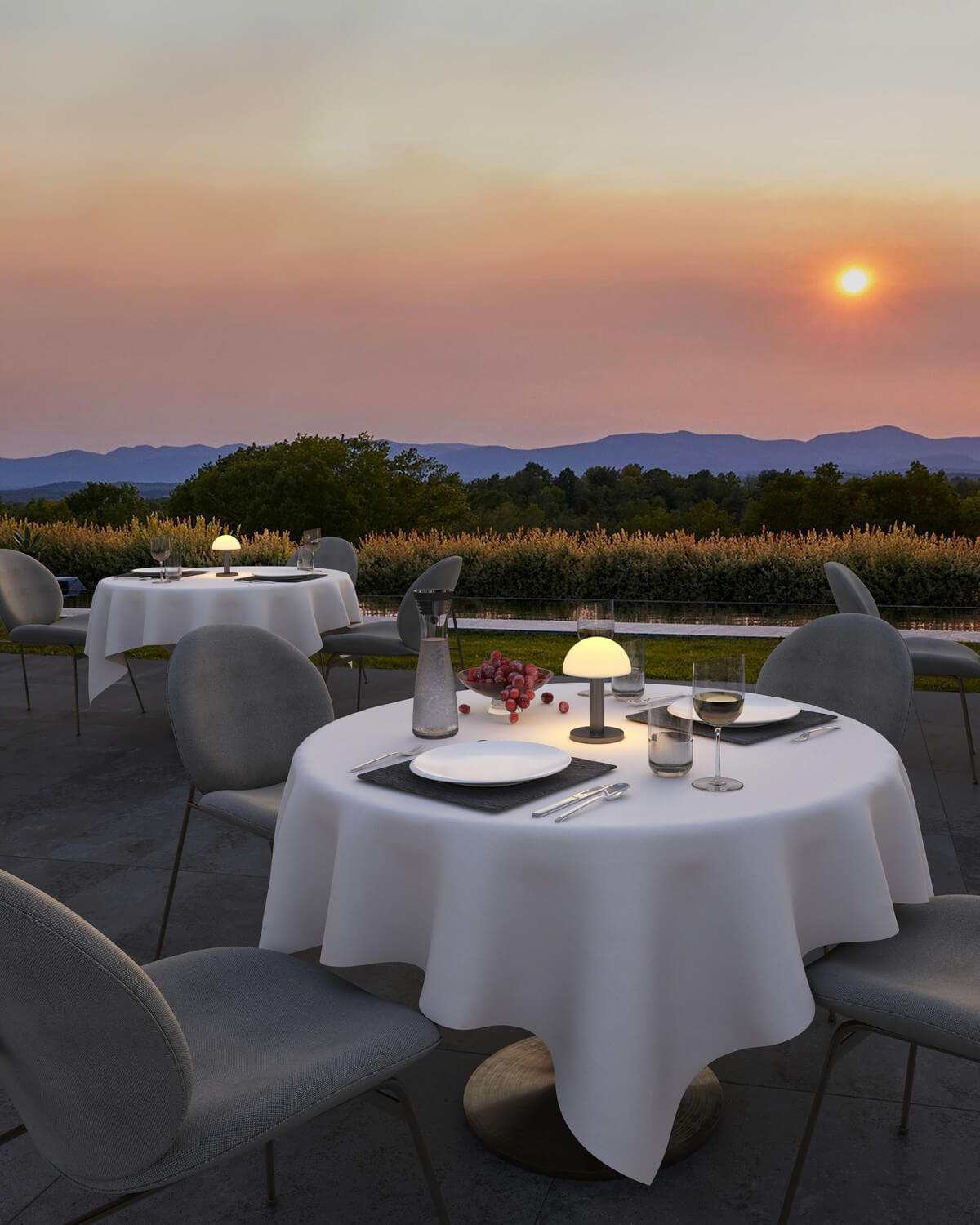 Terrasse de restaurant au coucher du soleil, plusieurs lampes posées sur les tables