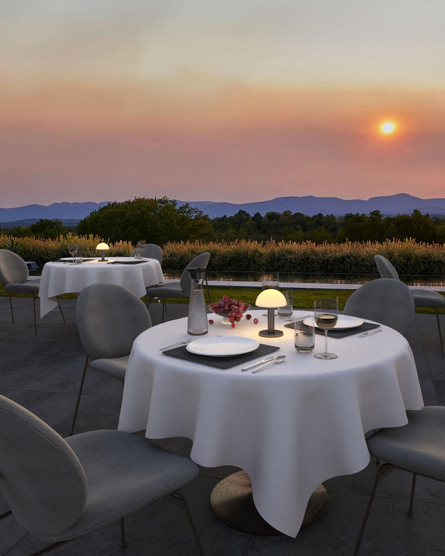 Terrasse de restaurant au coucher du soleil, plusieurs lampes posées sur les tables