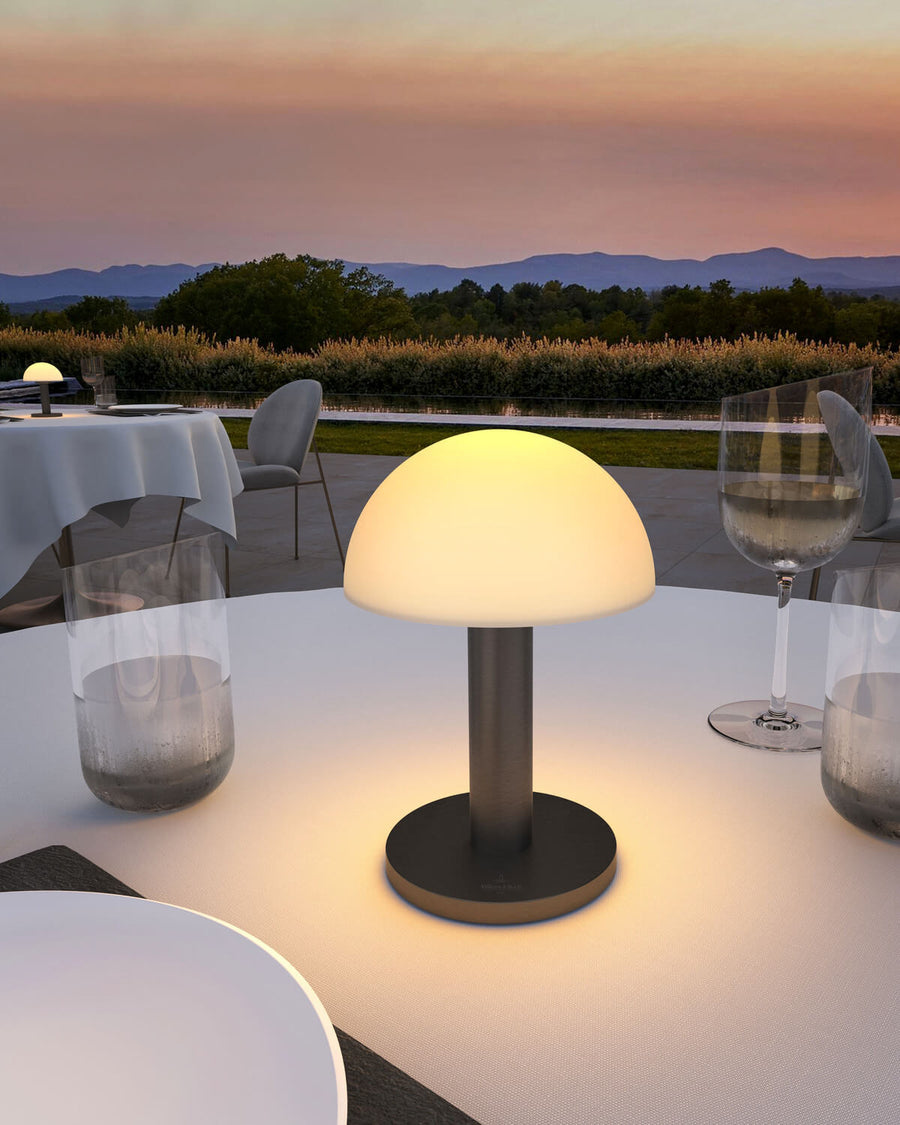 Gros plan du luminaire allumé au centre d'une table dressée avec verres