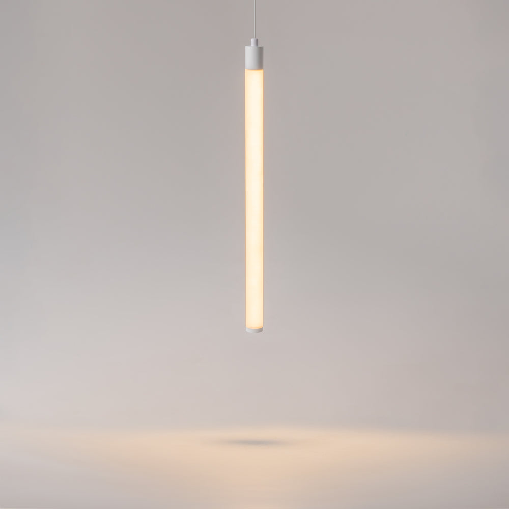 Vue de face du long tube lumineux blanc allumé, suspendu par un câble fin