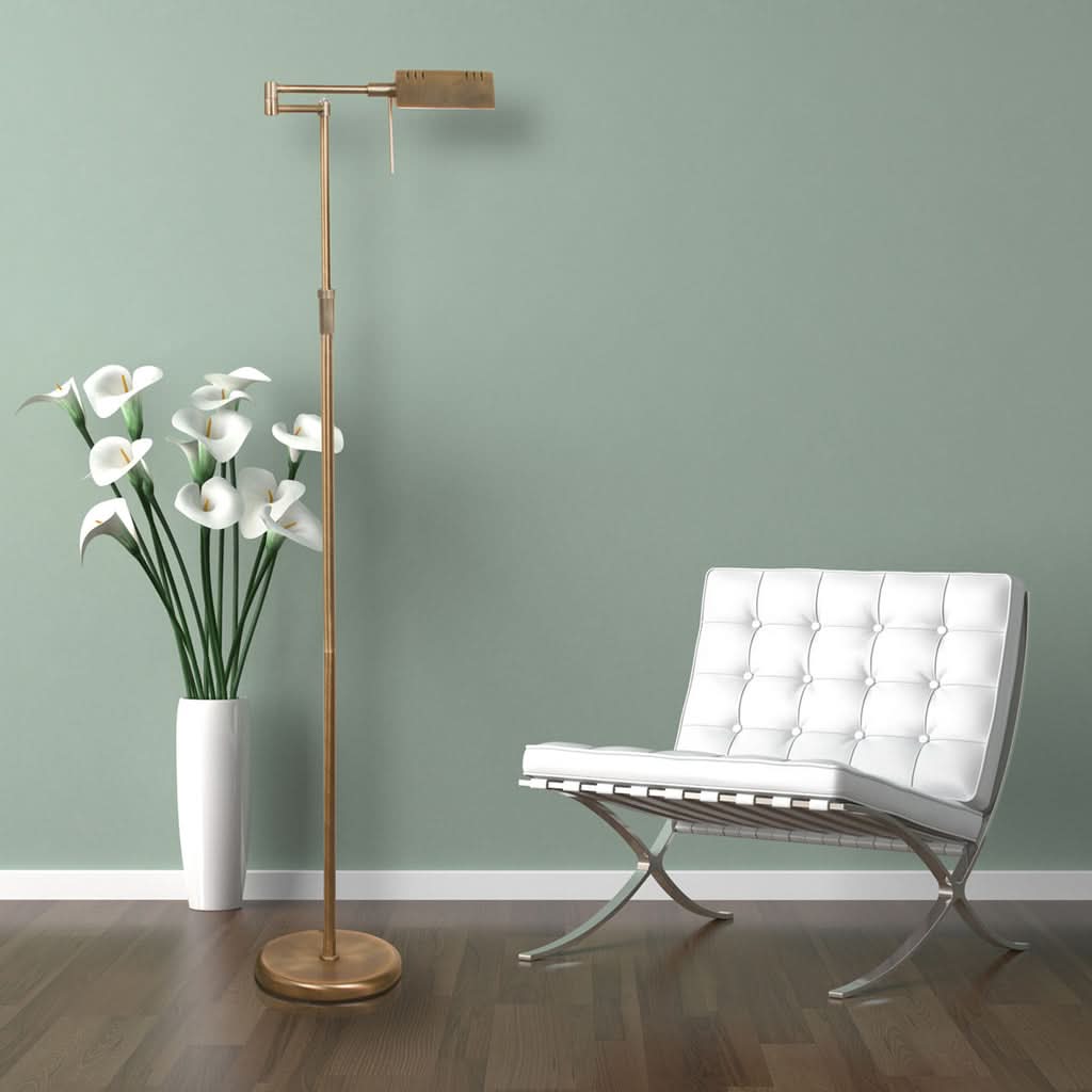 Mise en ambiance : lampadaire devant mur vert, fauteuil blanc et vase de fleurs