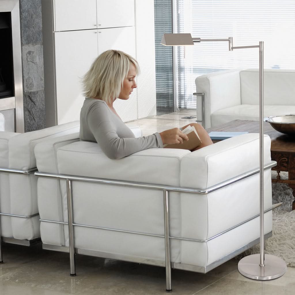Mise en ambiance, femme lisant dans un fauteuil blanc près de la lampe