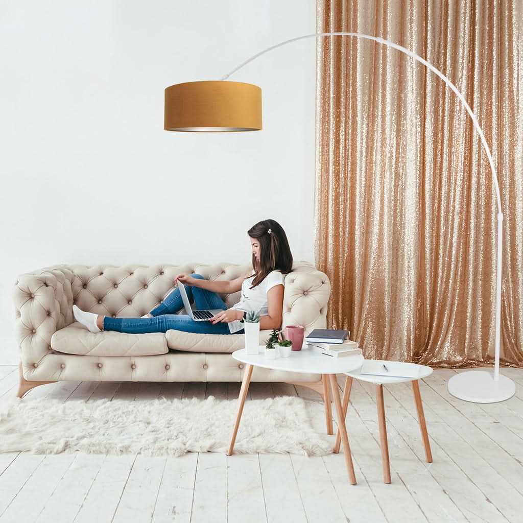 Mise en ambiance salon avec femme sur canapé sous le lampadaire arc