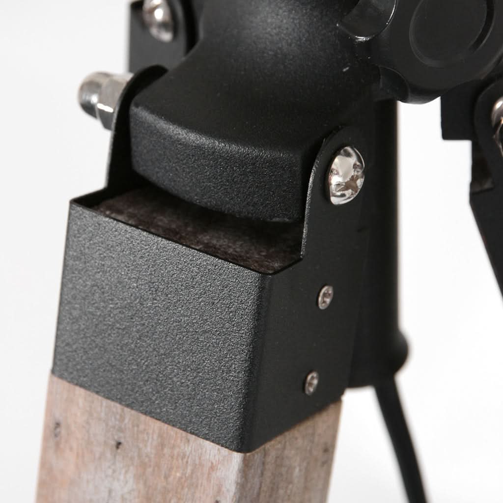 Plan serré sur le support métallique noir fixé au pied en bois avec boulons apparents.