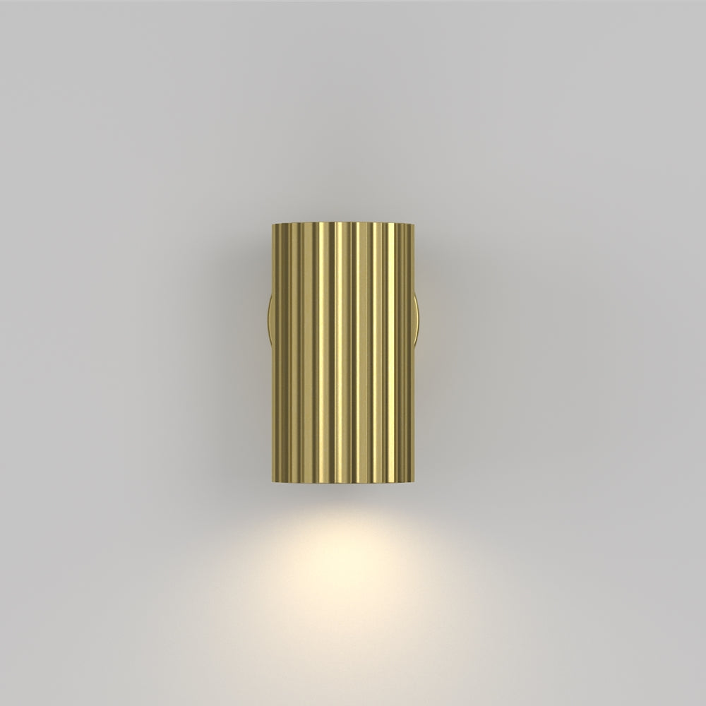Applique dorée allumée en ambiance, halo lumineux projeté sur le mur gris