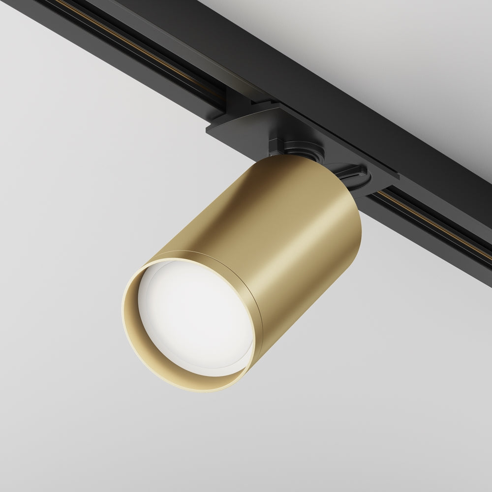 Projecteur doré mat orienté vers le bas, monté sur un rail noir au plafond