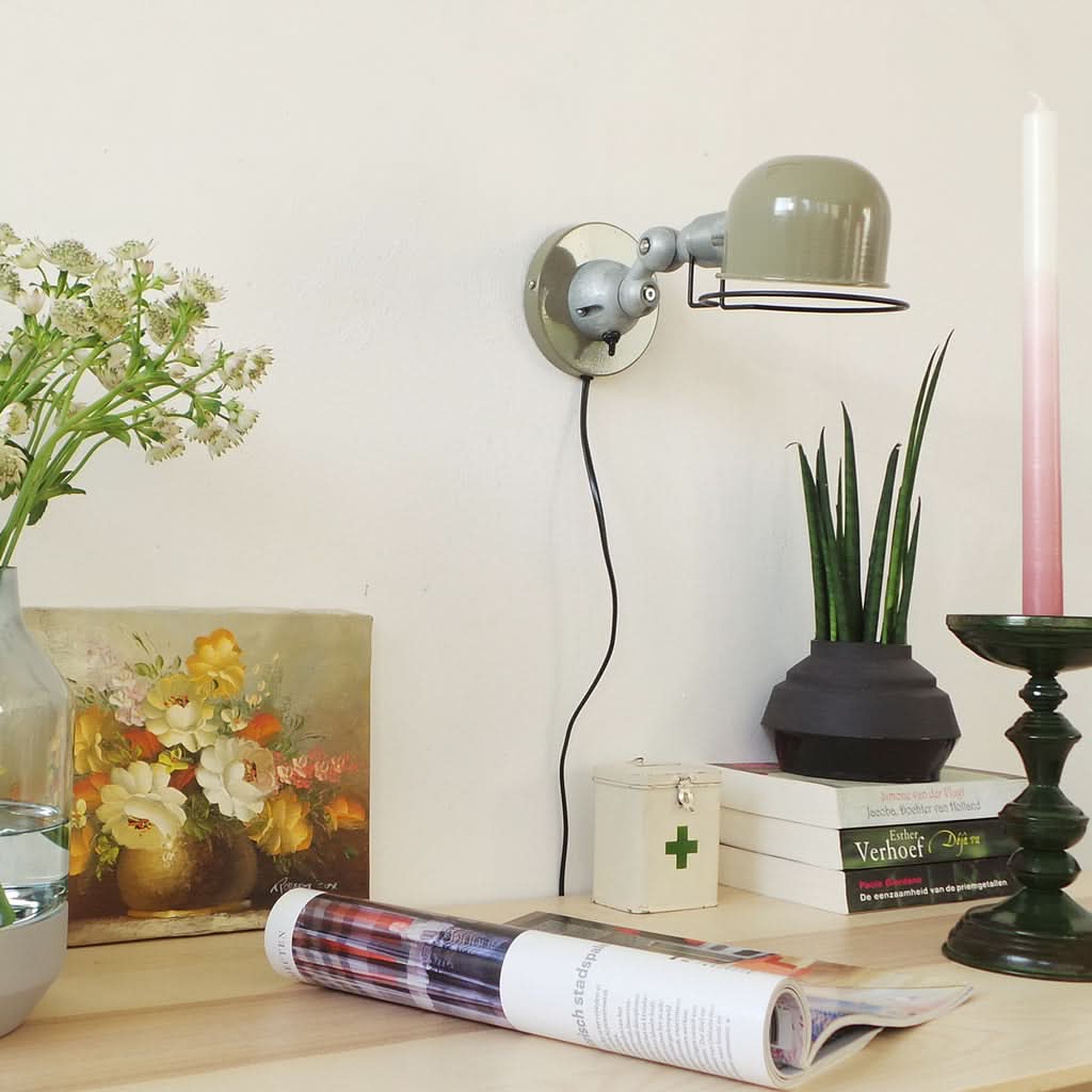 Mise en ambiance sur un mur blanc avec fleurs, tableau, plante et revues