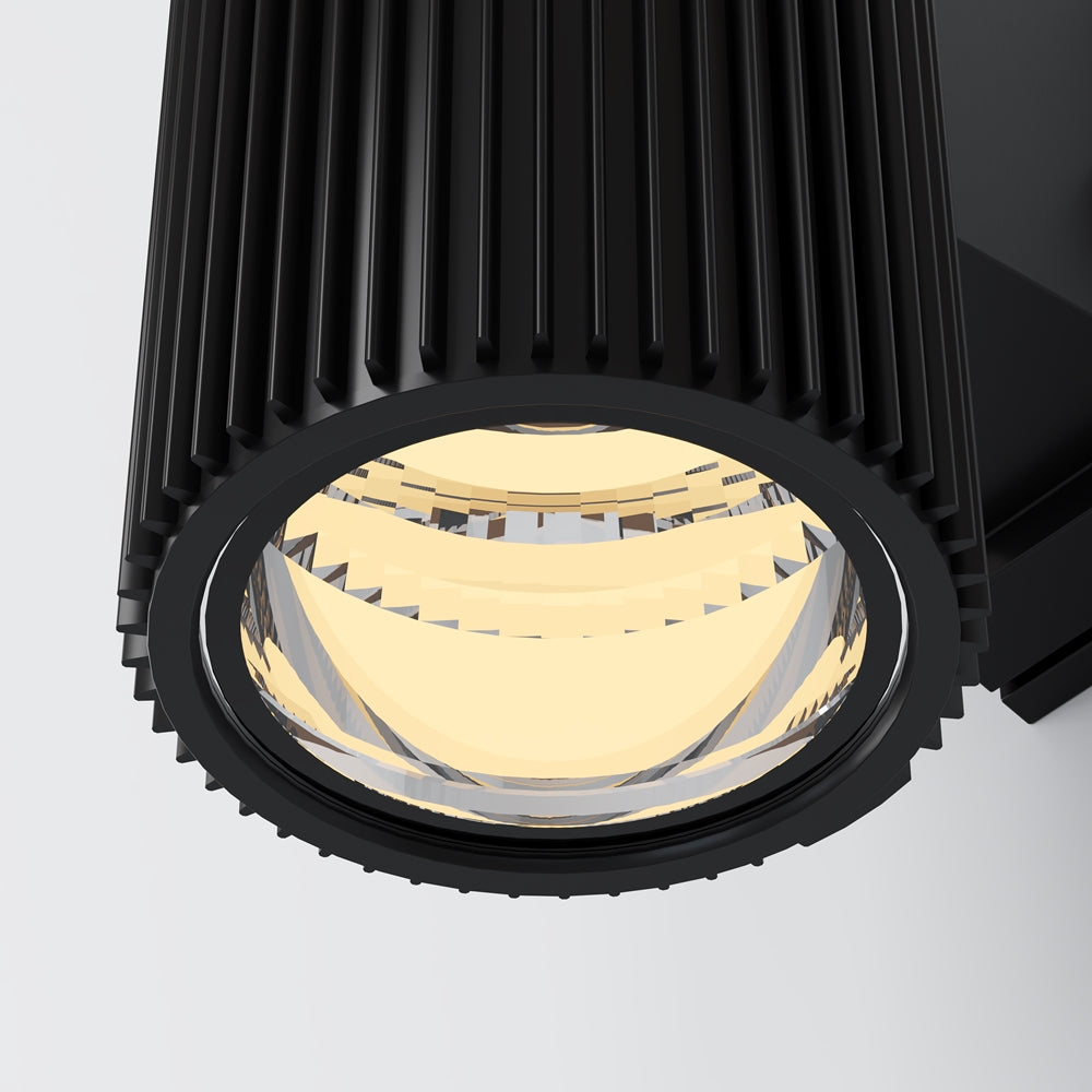 Gros plan sur la lentille optique dorée et la bague noire rainurée du luminaire