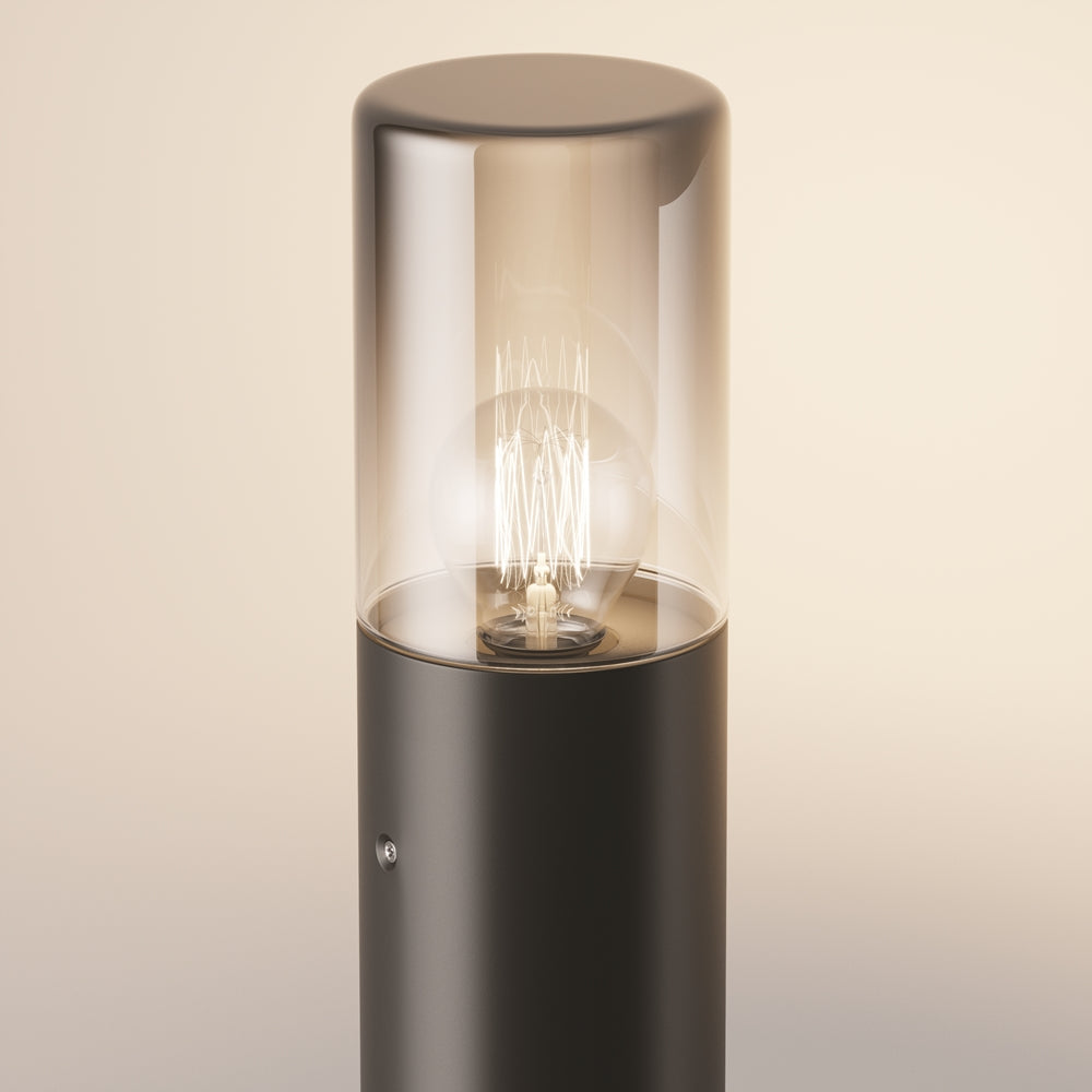 Gros plan du cylindre en verre fumé éclairé par l'ampoule à filament