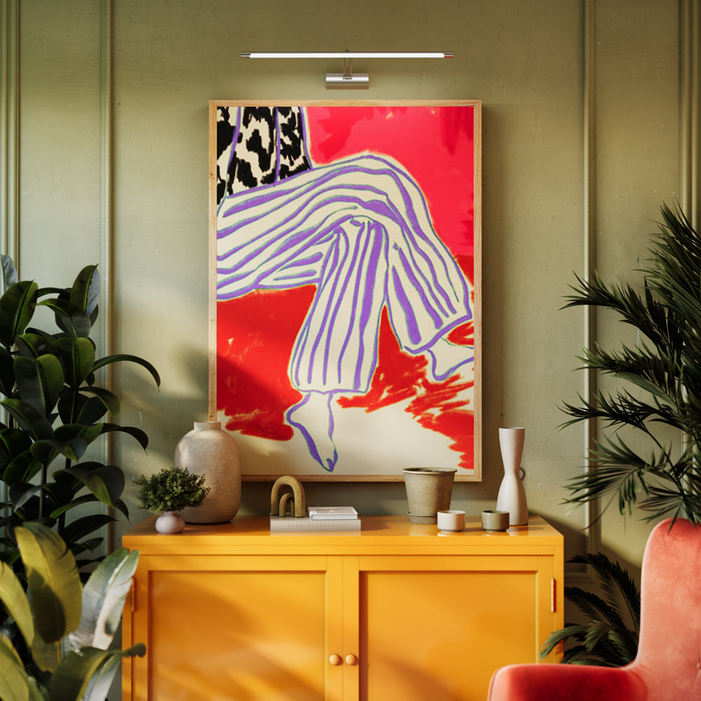Applique murale argentée éclairant un tableau coloré au-dessus d'un buffet jaune