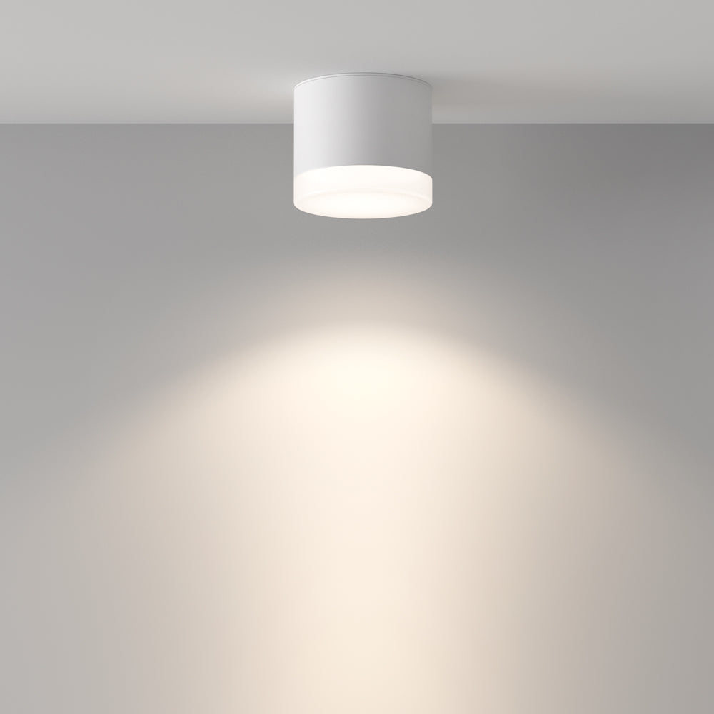 Mise en ambiance du plafonnier blanc allumé projetant un halo lumineux sur le mur