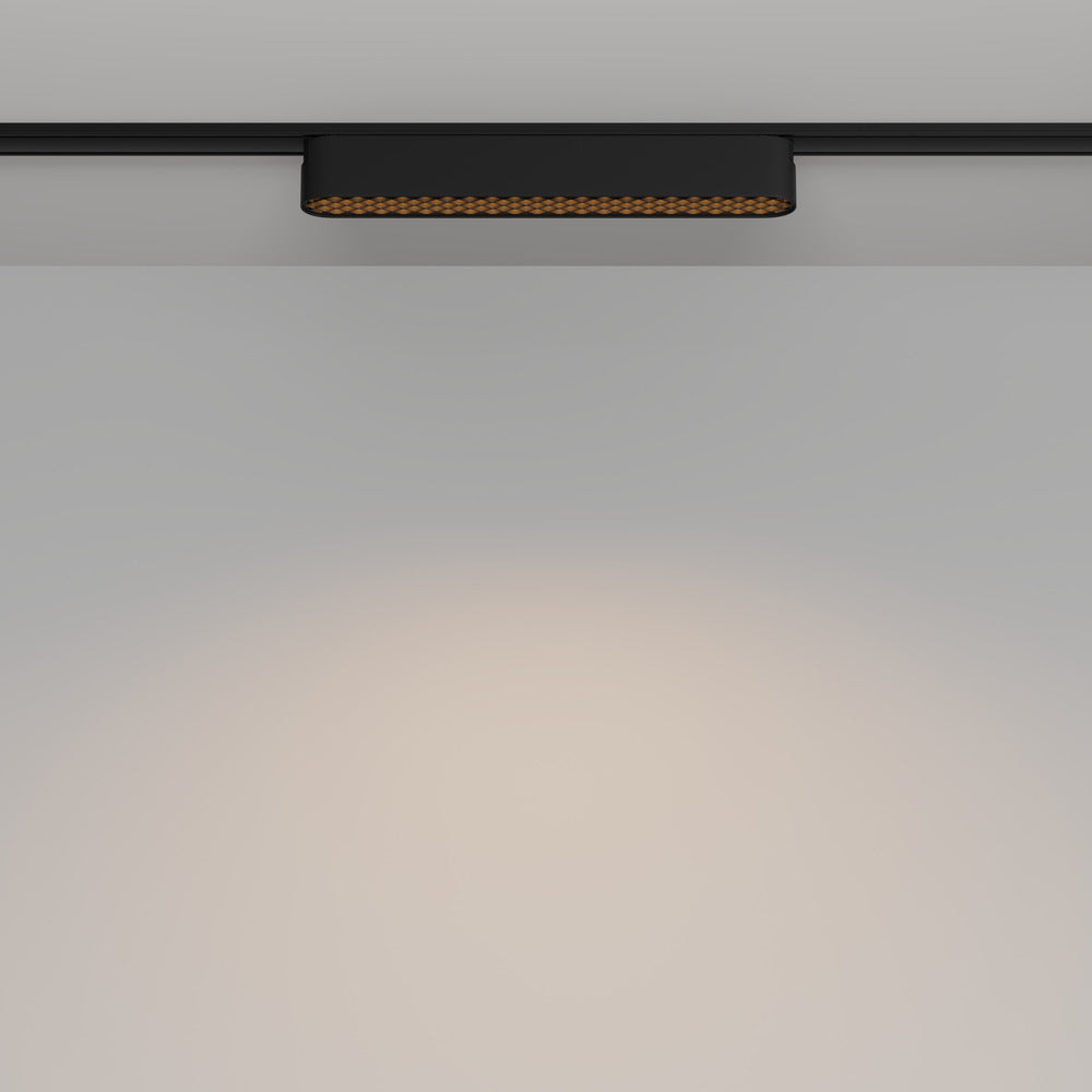 Spot monté sur rail au plafond diffusant un halo lumineux sur le mur