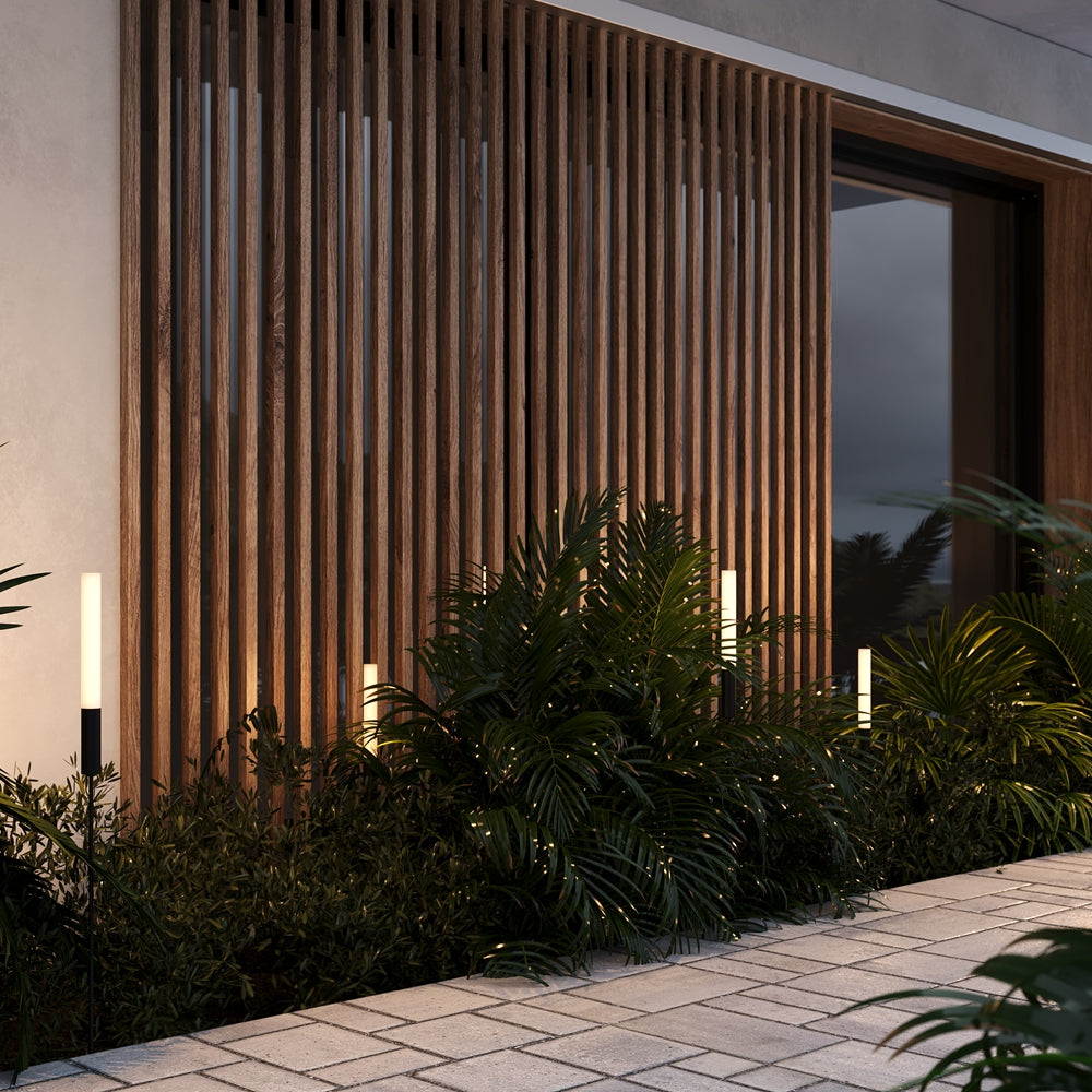 Mise en ambiance nocturne dans un jardin, luminaires éclairant une claustra en bois