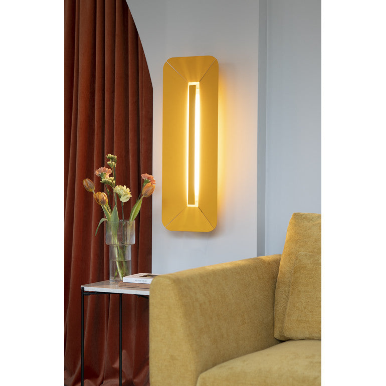 Mise en ambiance : applique jaune allumée sur mur gris, rideau et vase fleuri