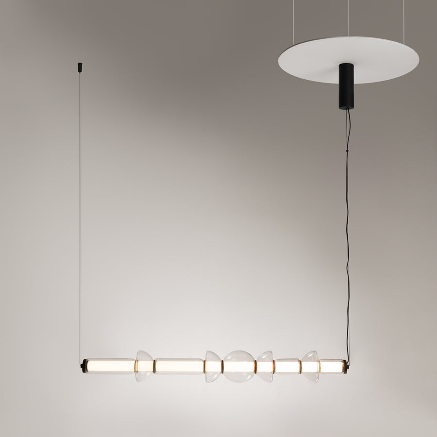Vue en situation du luminaire suspendu devant un mur beige clair uni