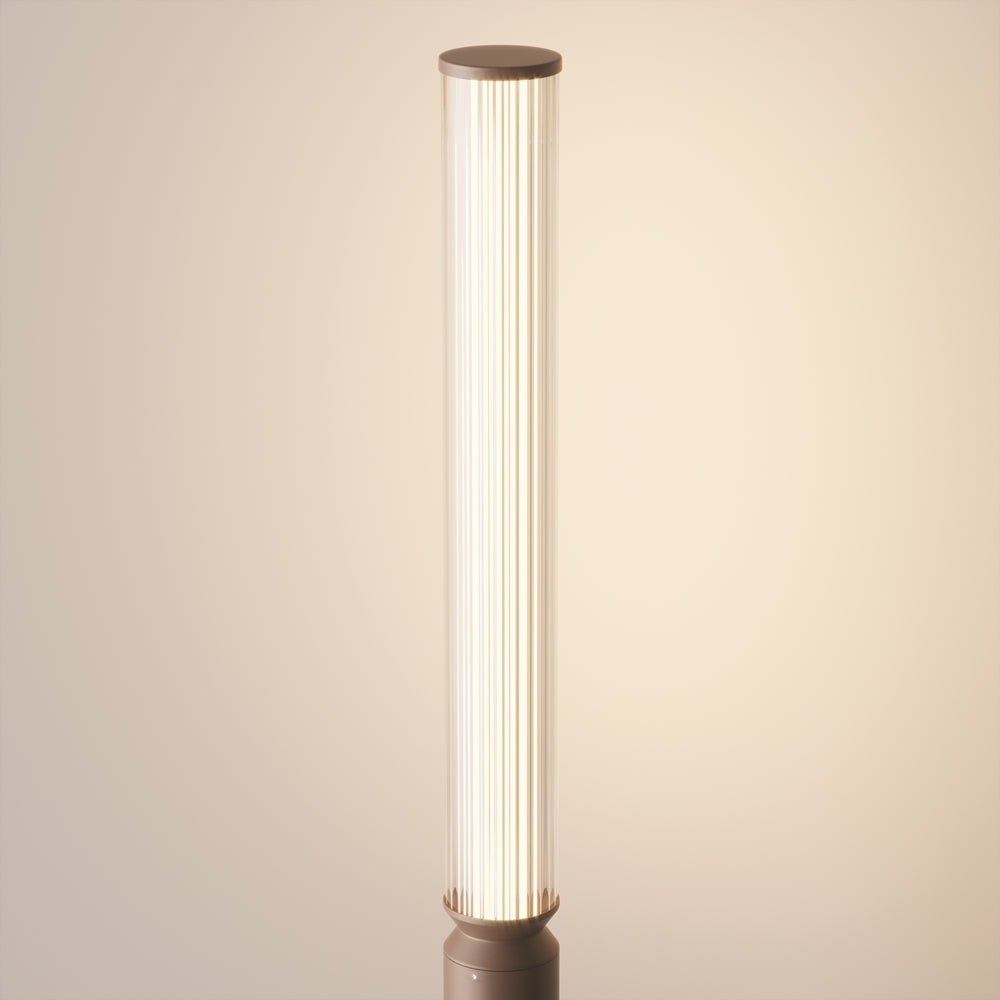 Vue rapprochée du haut du luminaire éclairé, cylindre translucide côtelé sur fond beige