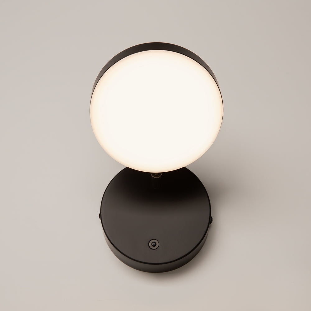 Produit de face sur fond beige, disque mural noir et diffuseur rond éclairé