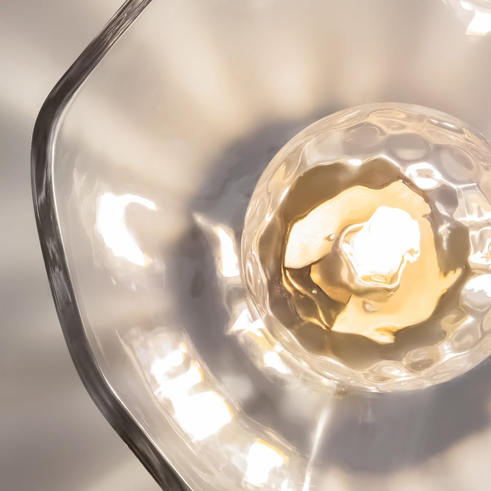 Gros plan sur le globe de verre martelé et l'ampoule allumée.