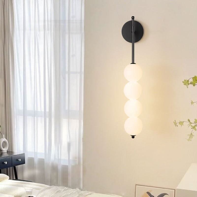 Version noire de l'applique murale à quatre globes, installée près d'une fenêtre à rideaux