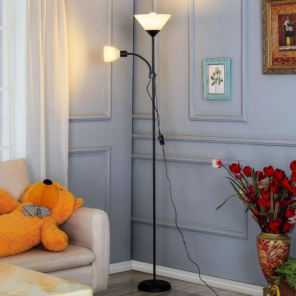 Lampadaire noir double éclairage installé dans un salon, près d'un fauteuil et d'un ours en peluche