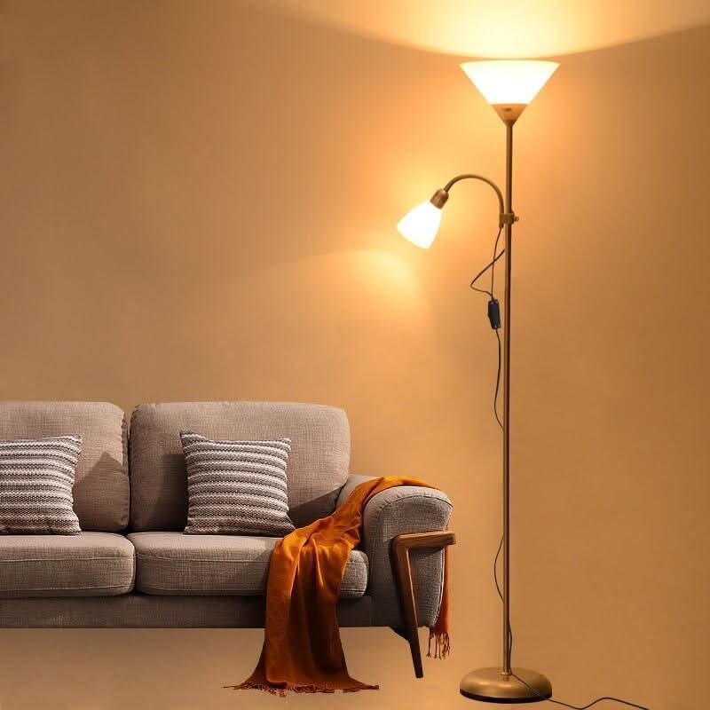 Lampadaire doré allumé près d'un canapé gris, ambiance chaleureuse dans un intérieur