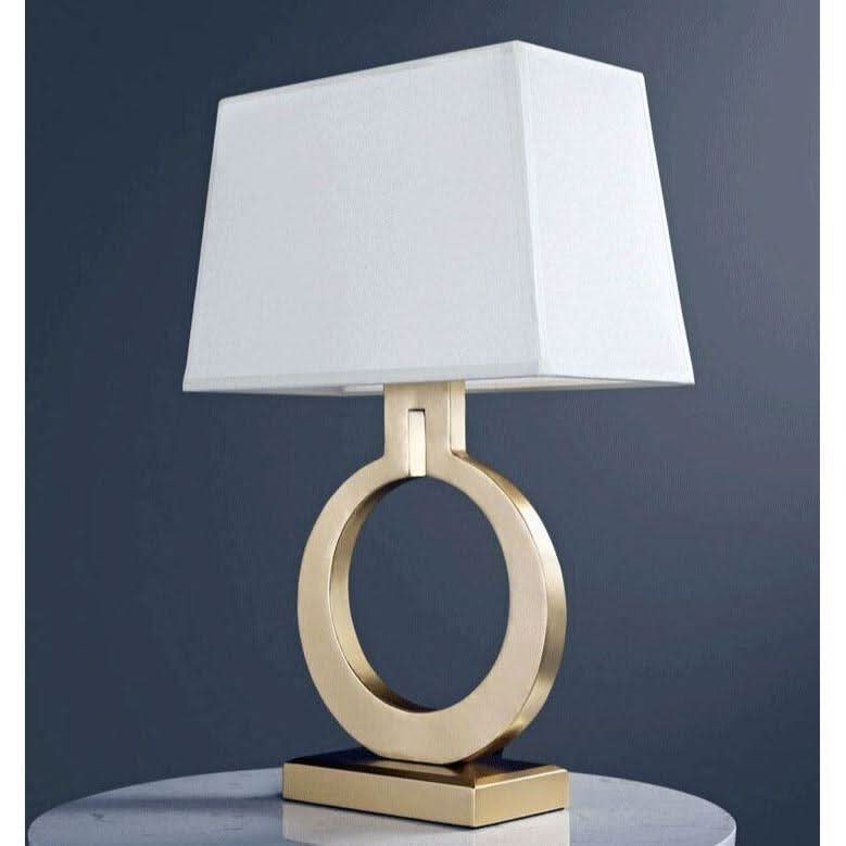 Lampe éteinte sur fond bleu-gris, abat-jour rectangulaire blanc et socle doré circulaire.