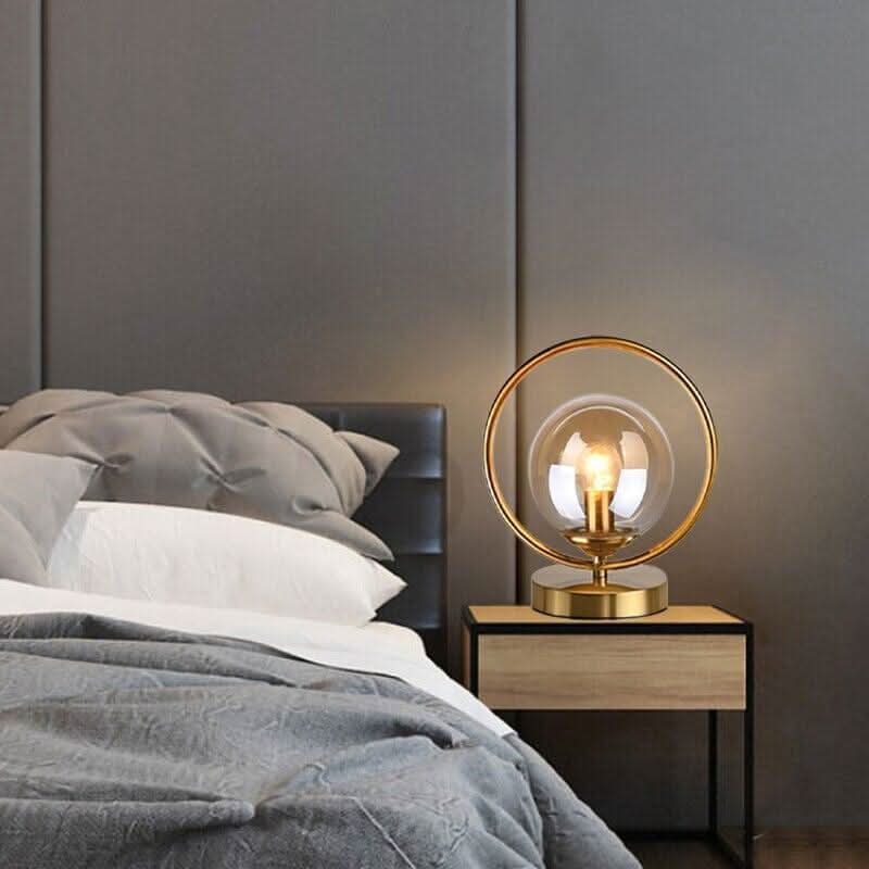 Lampe de chevet dorée allumée sur table de nuit dans une chambre grise