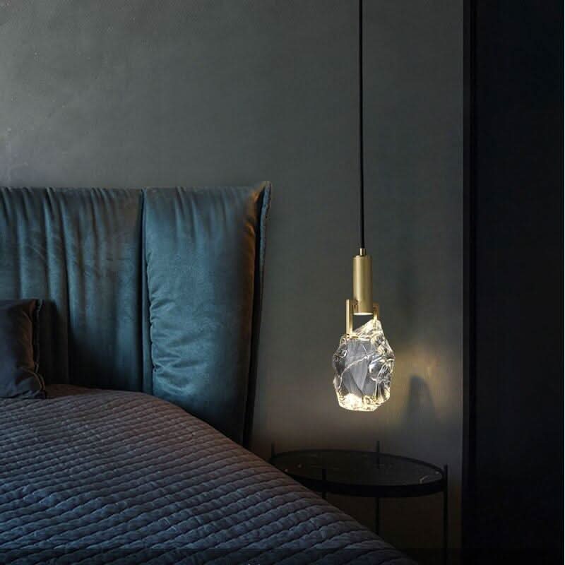Lampe suspendue éclairant une chambre avec tête de lit bleu nuit et table ronde.