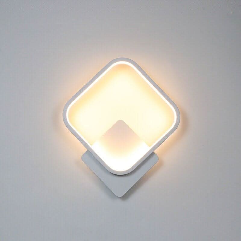 Modèle blanc carré arrondi en diagonale, éclairage chaud et découpe centrale.