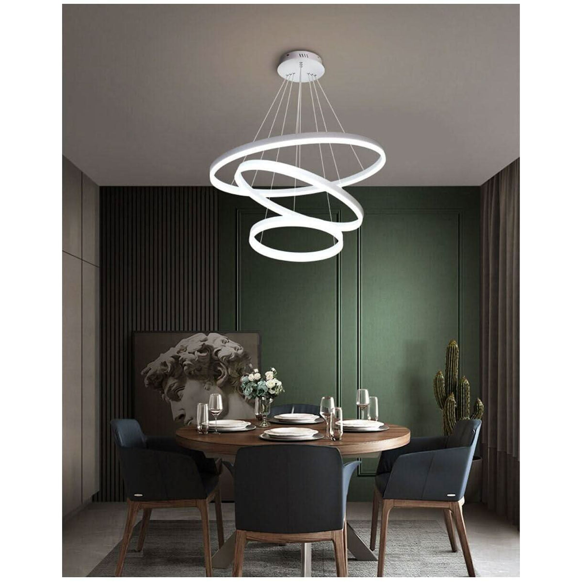 Suspension blanche à cercles entrelacés éclairant une salle à manger verte.