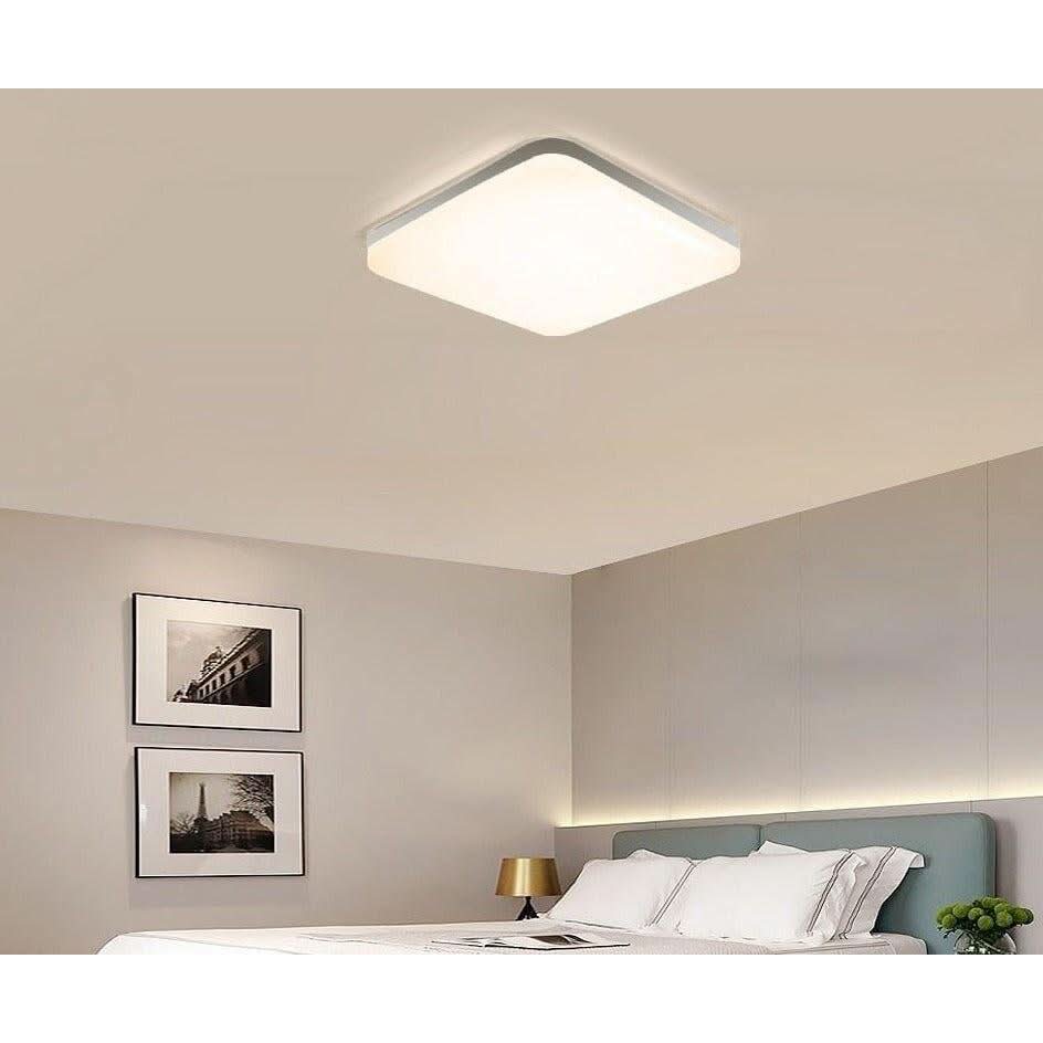 Plafonnier blanc carré éclairé au-dessus d'un lit, ambiance chambre douce
