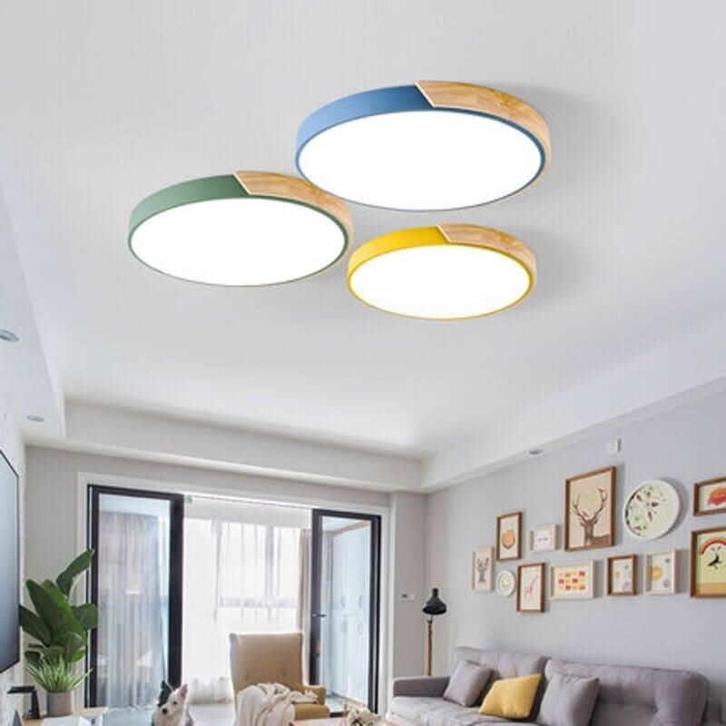Trois plafonniers ronds bleu, vert et jaune allumés au plafond d'un salon